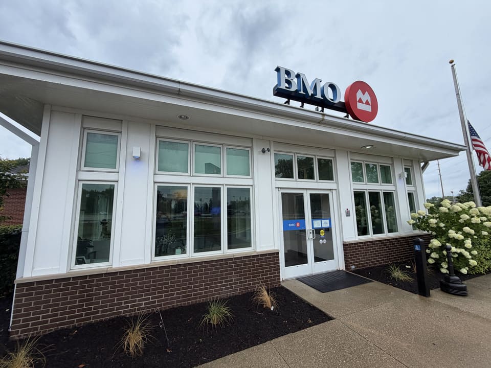 Bank branch with white siding and brick base after a commercial wash