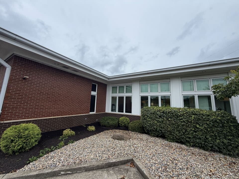 Side of a bank branch with clean white siding and landscaping