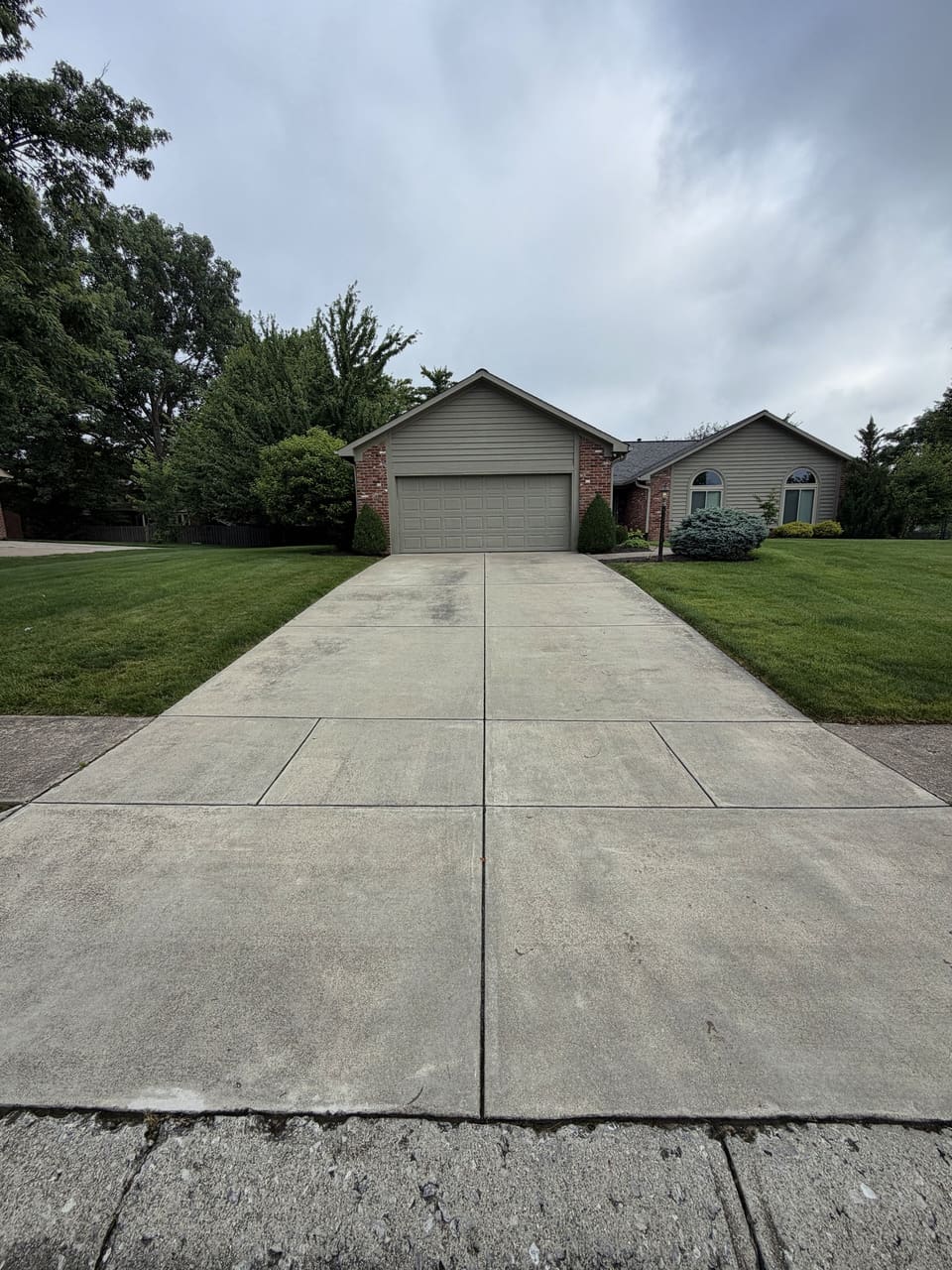 Long clean driveway leading to a brick and siding ranch home