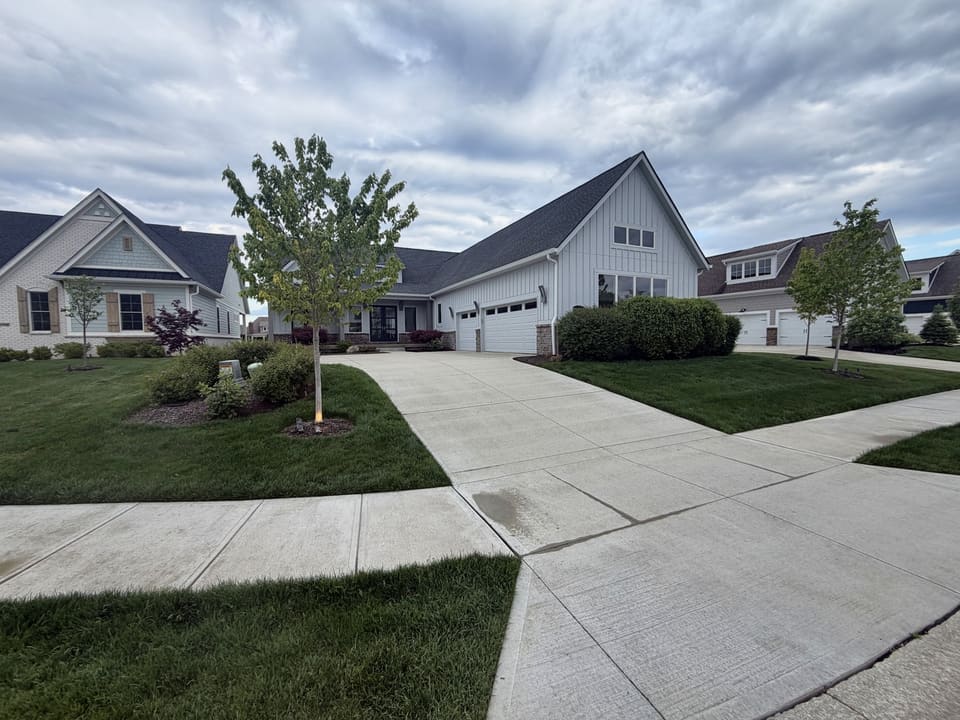 Driveway and sidewalk washed clean in front of two white farmhouses