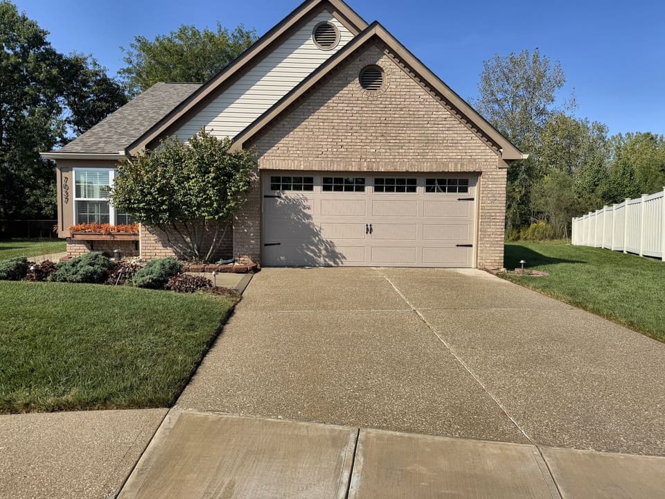 Clean driveway in front of a brick home with a round gable window