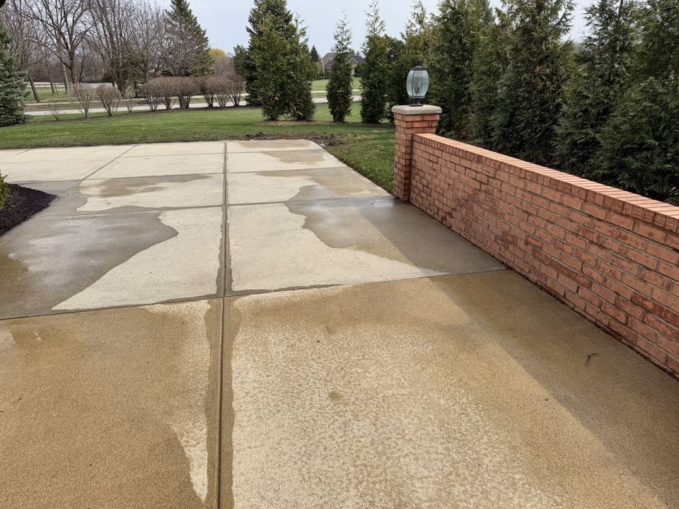 Driveway along a brick wall drying after a pressure wash