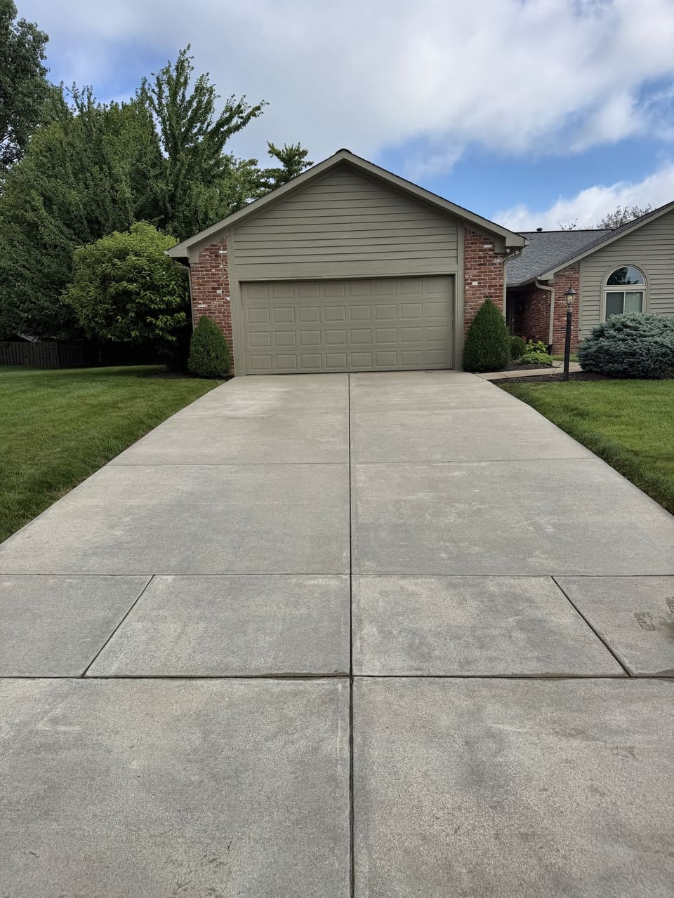 Clean concrete driveway in front of a tan ranch home