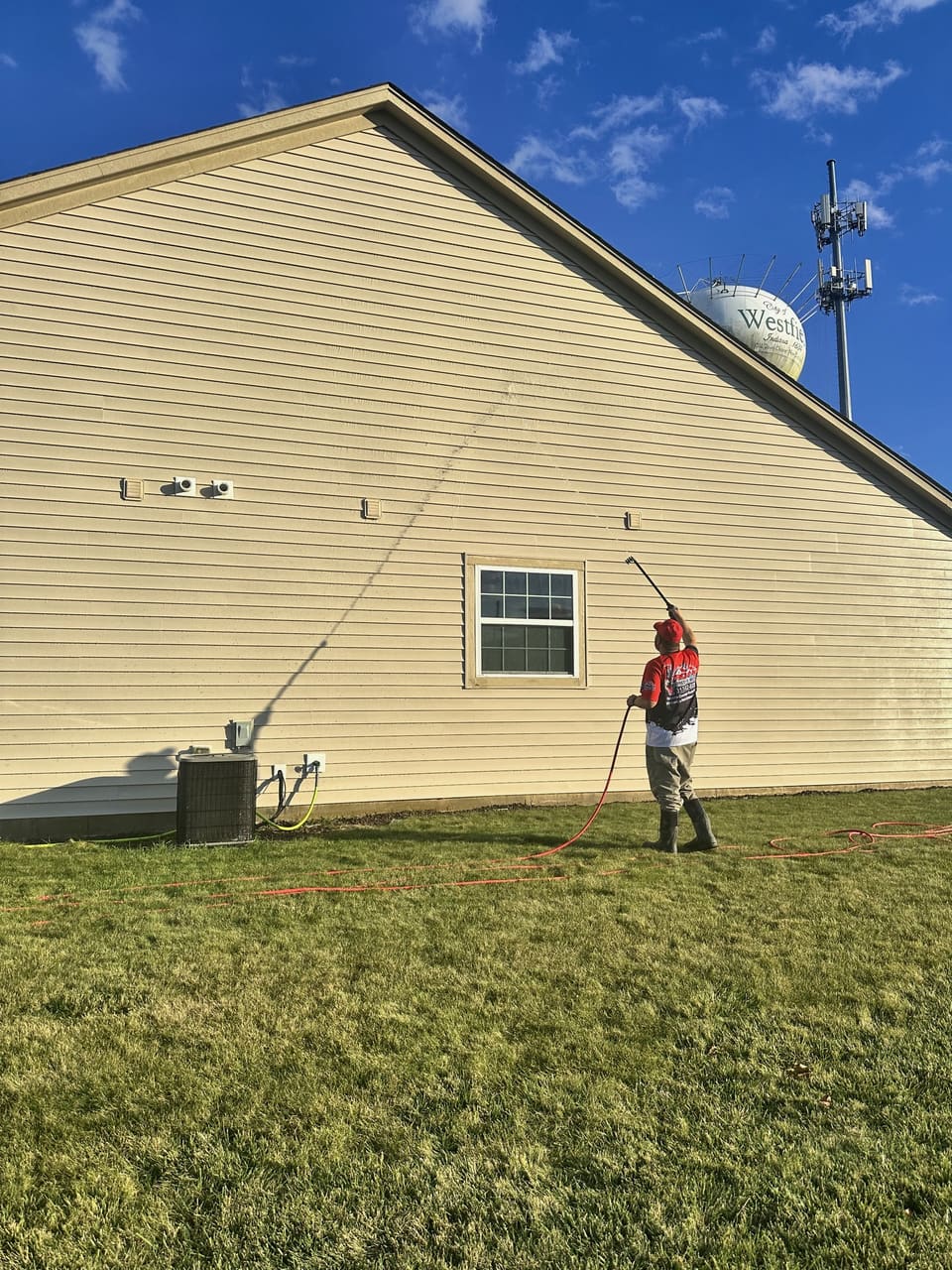 Trojan soft washing the tall gable wall of a two story home