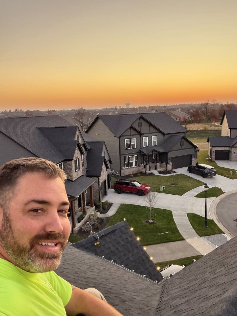 A Trojan crew member on a rooftop at sunset over a Westfield area neighborhood
