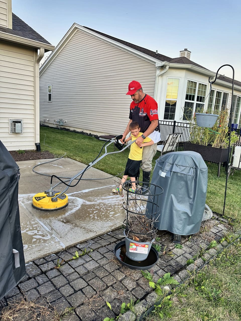 Trojan running a surface cleaner across a back patio