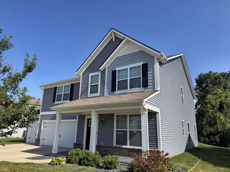Two story home with blue gray siding and white trim after a house wash