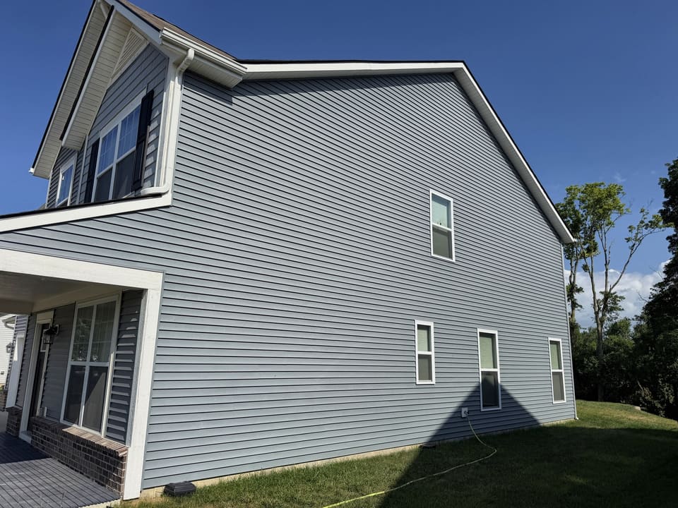 Side wall of a two story home with clean blue gray vinyl siding