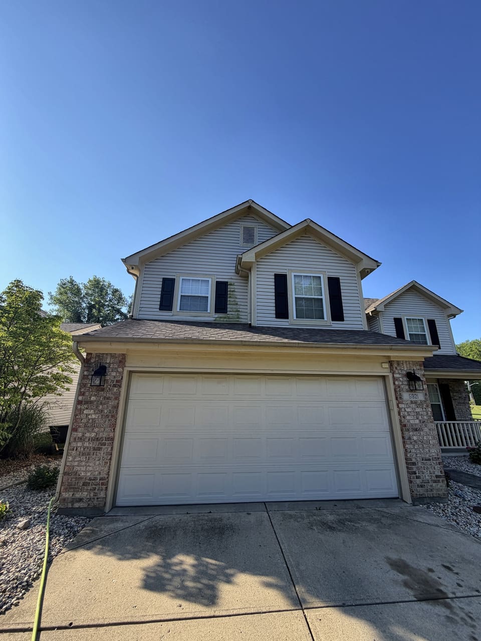 Cream two story home with a two car garage after soft washing