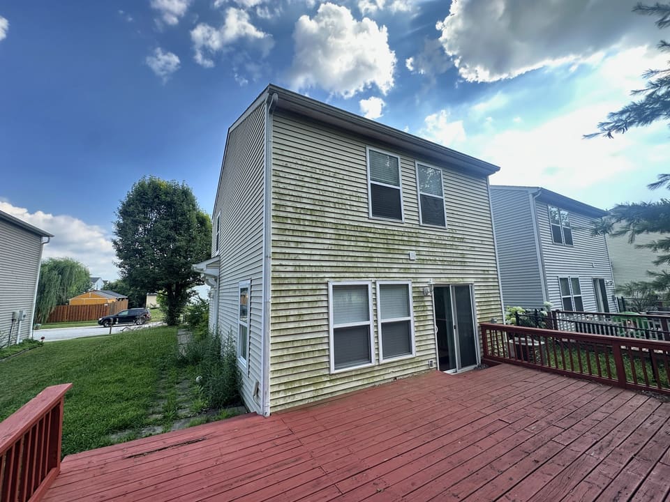 Back of a two story home with clean siding above a red deck