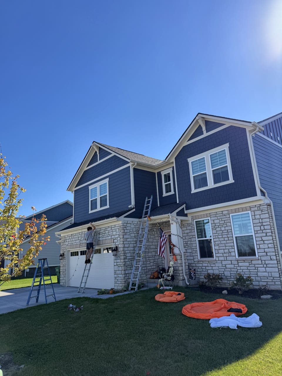 Navy and white two story home with stone front during a house wash