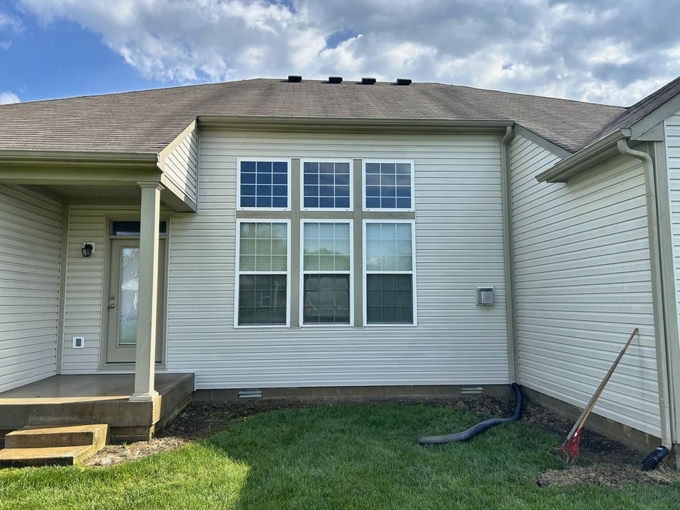Back of a vinyl home with a tall bank of windows after soft washing