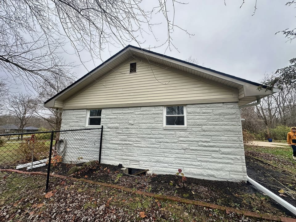 Cream siding and white stone skirting on a ranch home after a wash