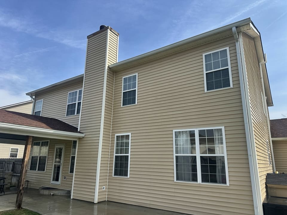 Tan two story home with a siding chimney chase after soft washing
