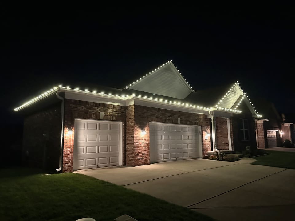 Brick ranch lit with warm white bulbs along the eaves and both gables