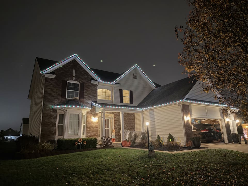 Brick and siding home with cool white lights along the roofline