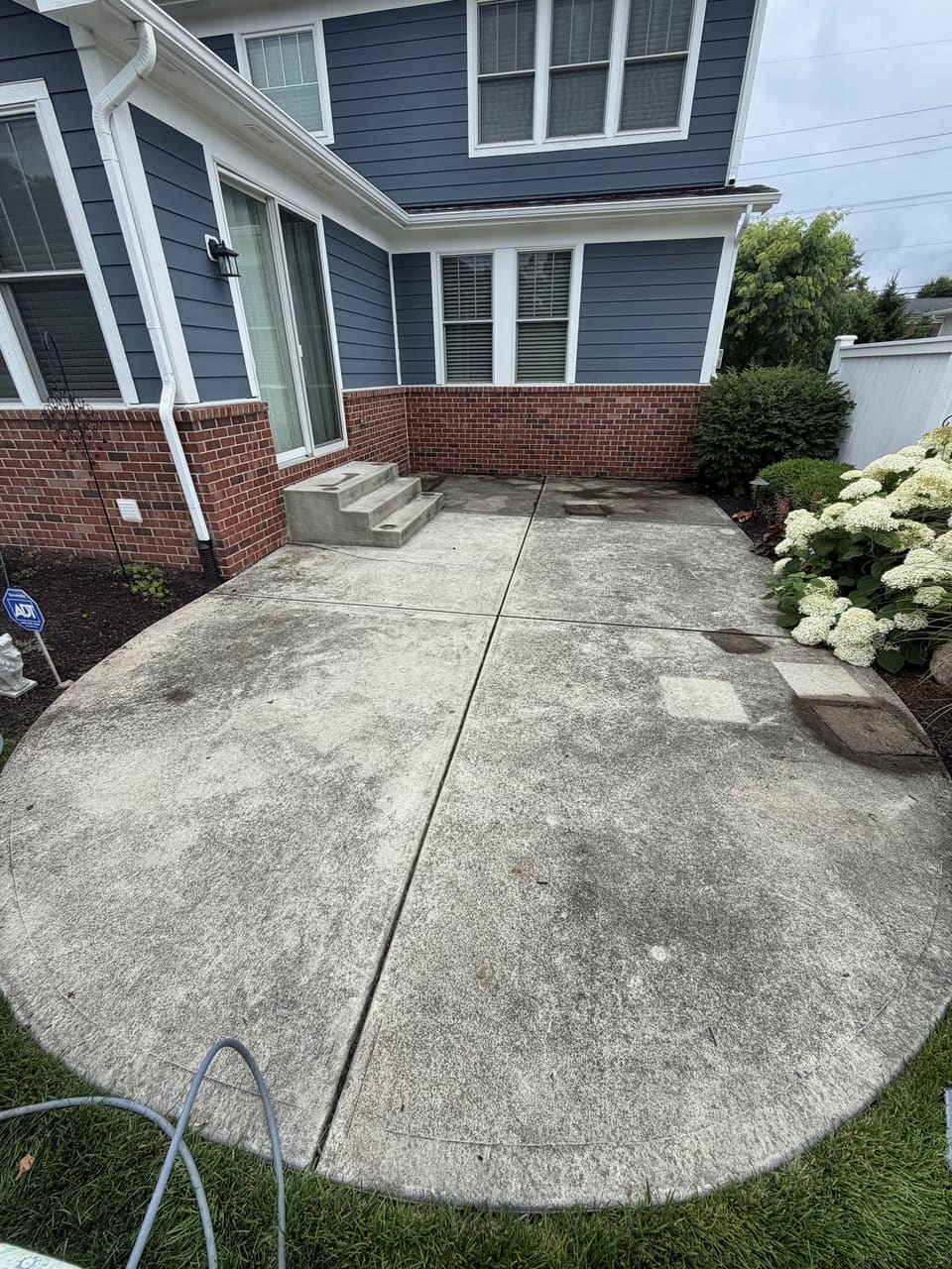 Curved back patio washed clean behind a blue and brick home