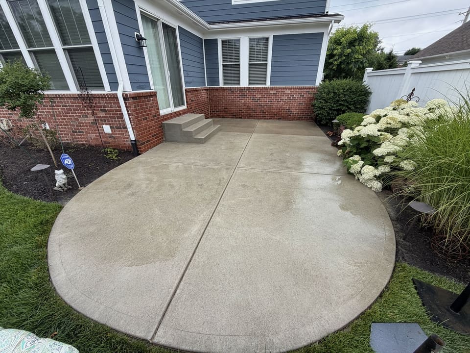 Round concrete patio beside a blue home with white hydrangeas