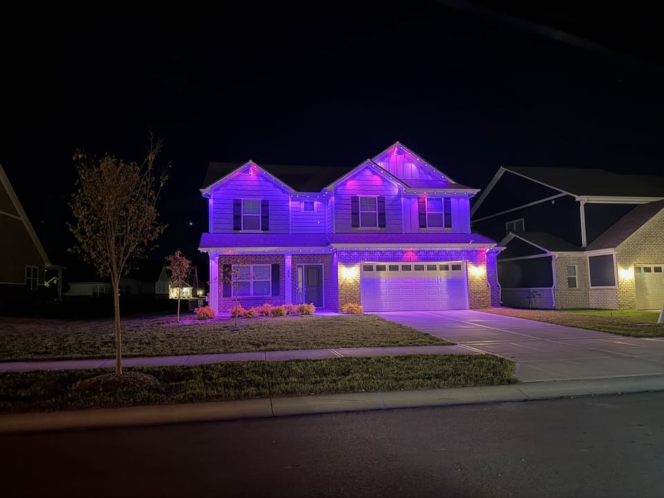 Two story home with permanent roofline lights set to purple