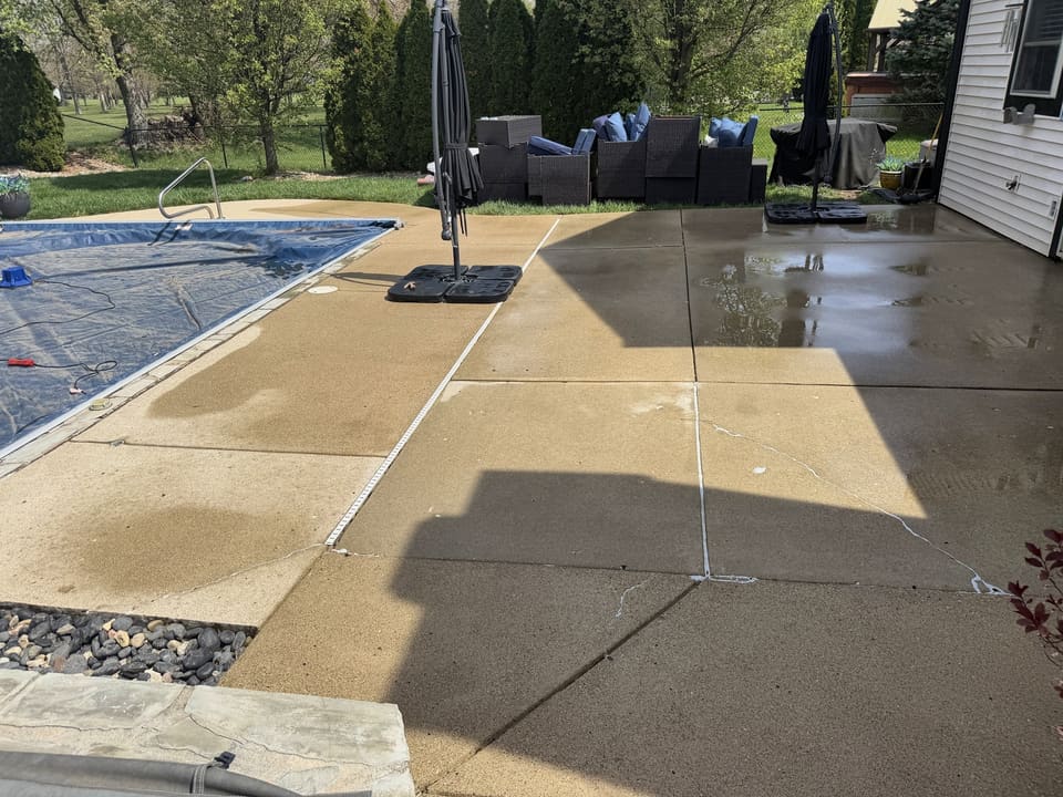 Large concrete pool deck and patio washed clean around a covered pool