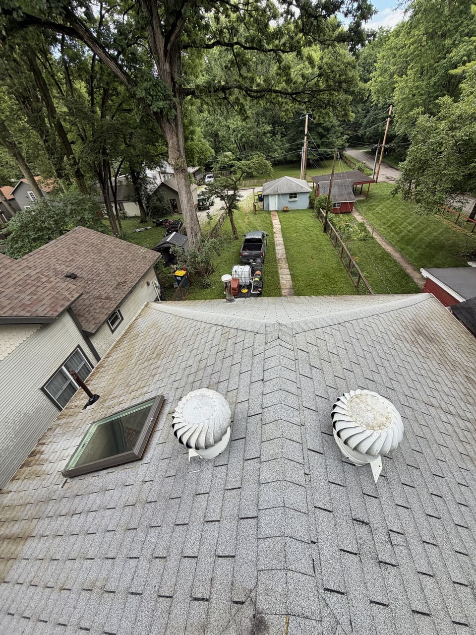 Light gray asphalt shingle roof with two turbine vents after a roof wash