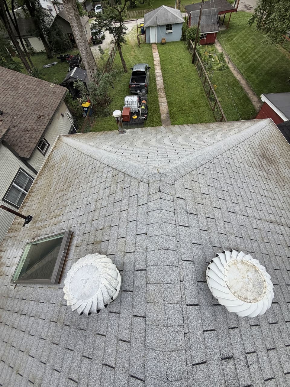 Clean shingle roof with turbine vents and a skylight, seen from the ridge