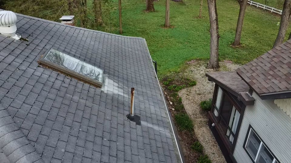 Shingle roof with a skylight and vent pipe during a roof wash