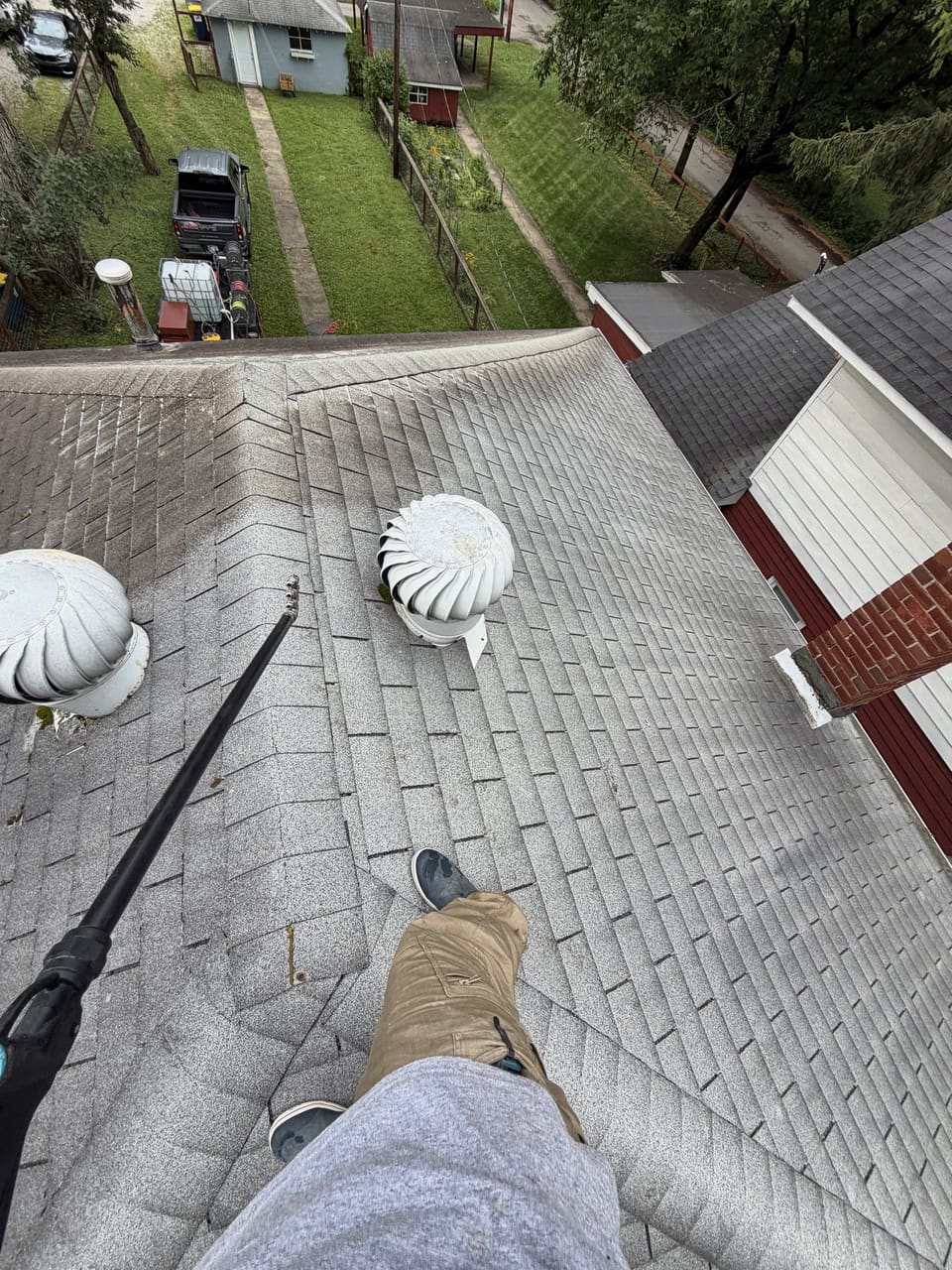 Soft wash wand on a shingle roof, seen from where the crew stands on the ridge