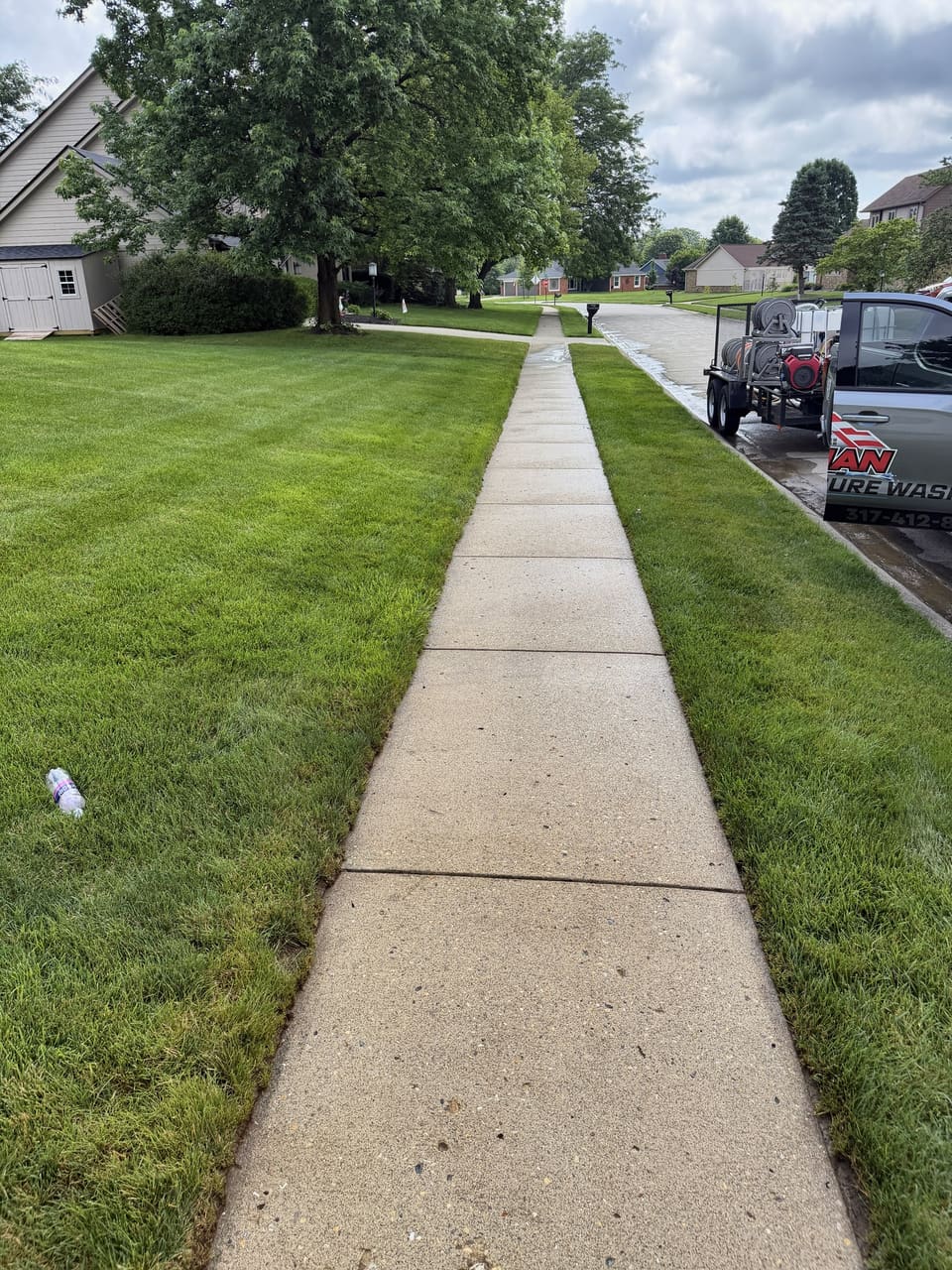 Long public sidewalk washed bright beside a green lawn