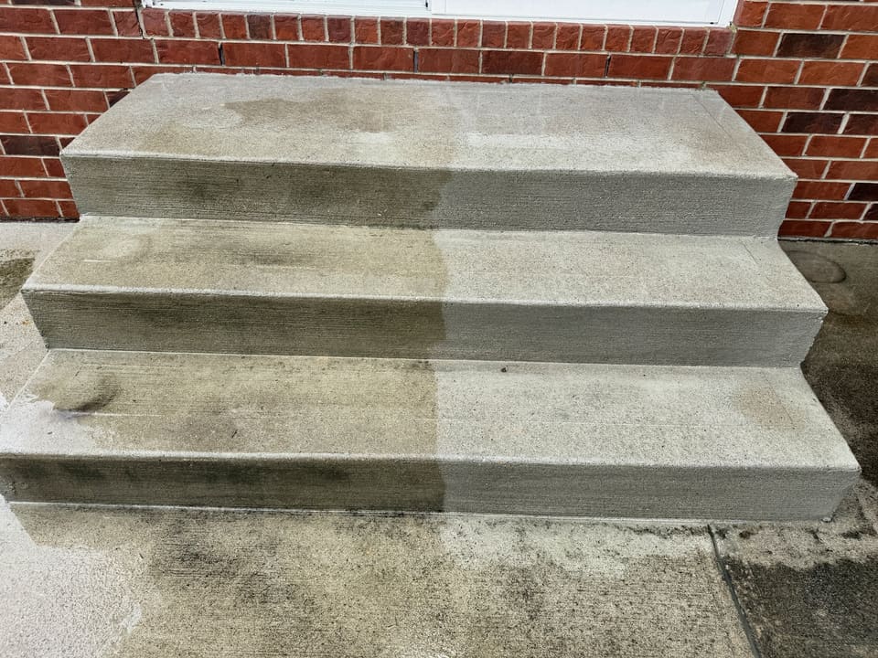 Concrete front steps halfway through cleaning, clean on one side and dirty on the other