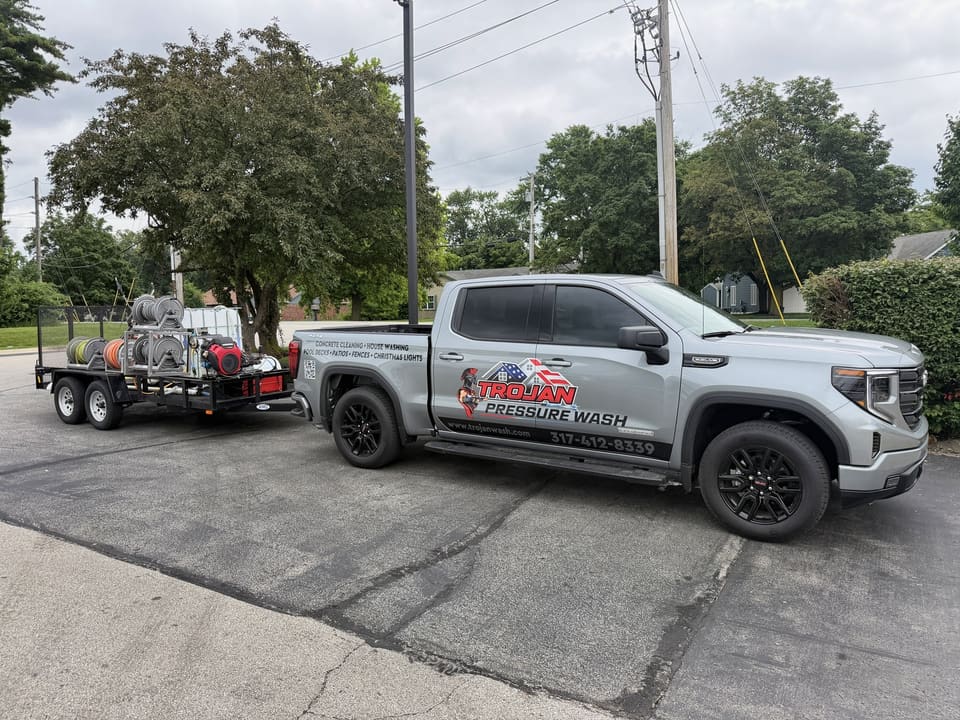 Trojan Pressure Wash truck and equipment trailer parked on a driveway